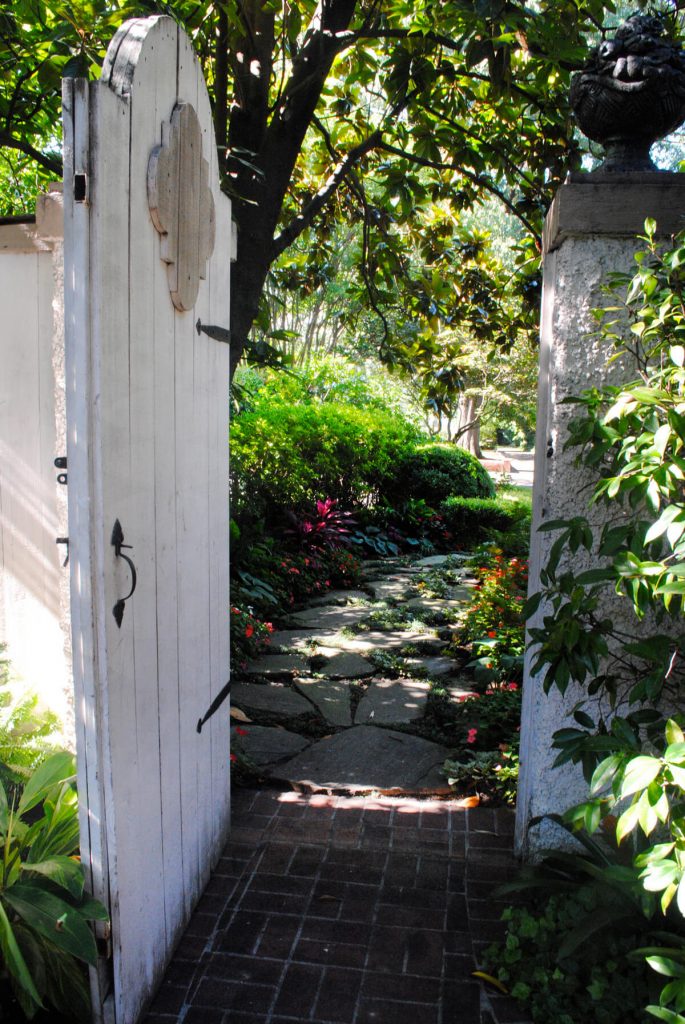 This garden gate with stuccoed pillars in Nashville was designed by Gurley’s Azalea Garden and leads to a brightly flowered garden path.